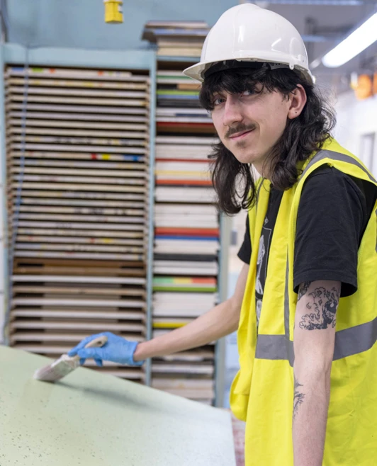 Painting and decorating student smiling while painting large board in workshop Painting and decorating student smiling while painting large board in workshop